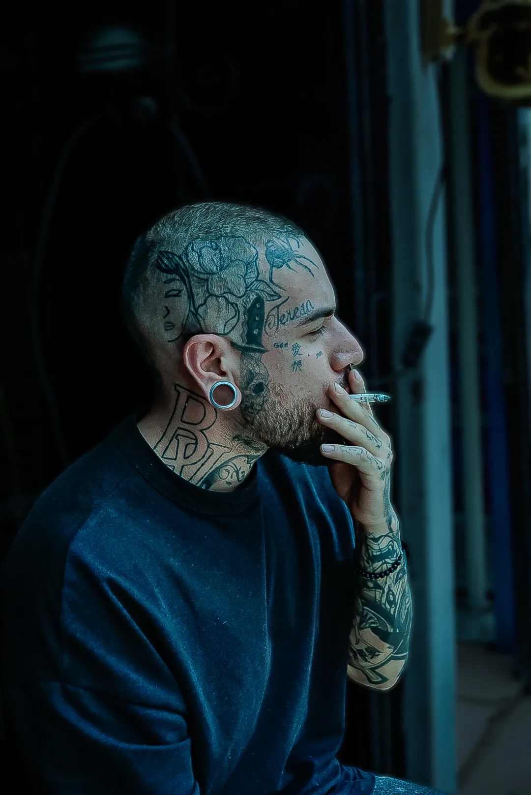 Retrato de hombre tatuado fumando de perfil