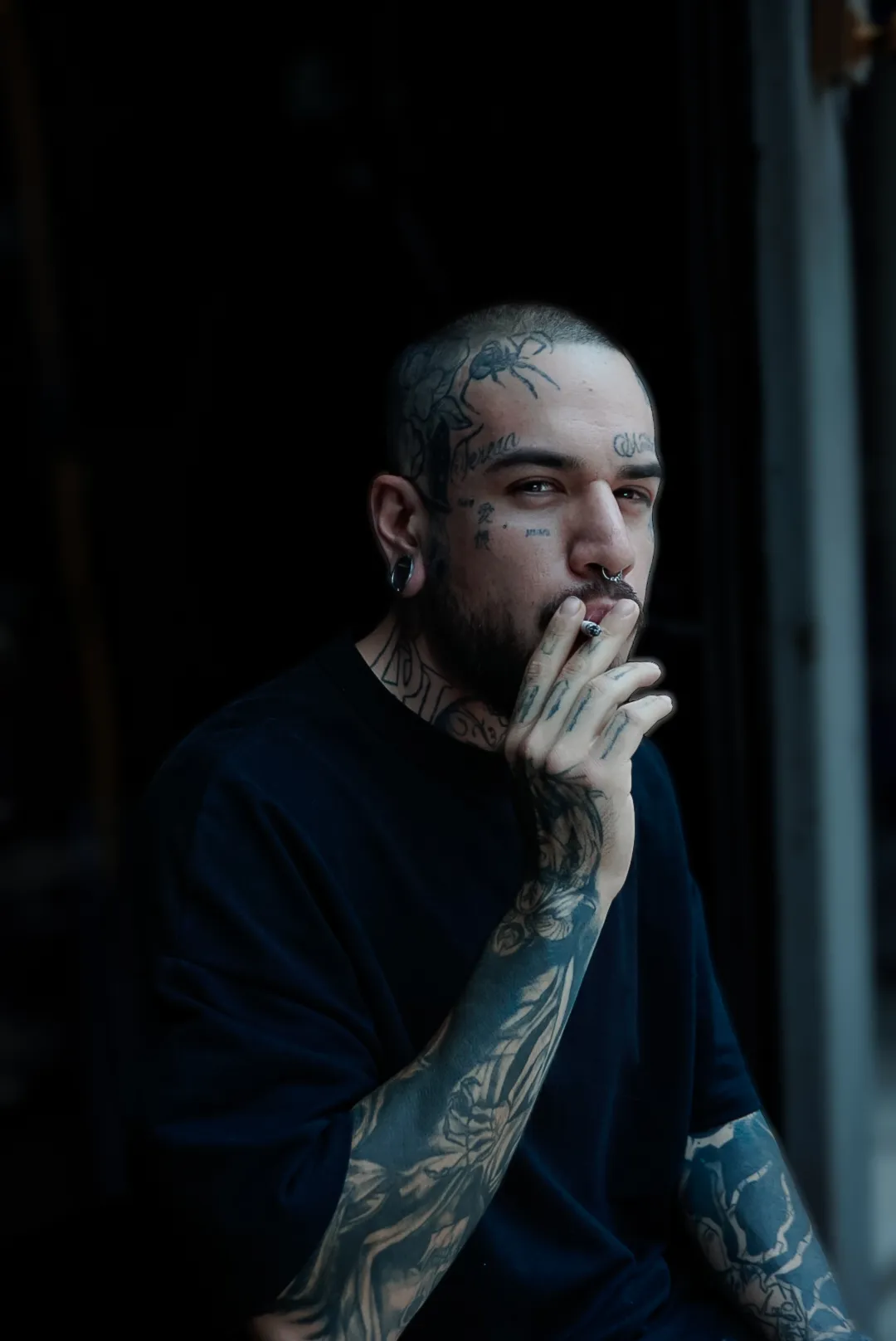 Retrato de hombre tatuado fumando en penumbra